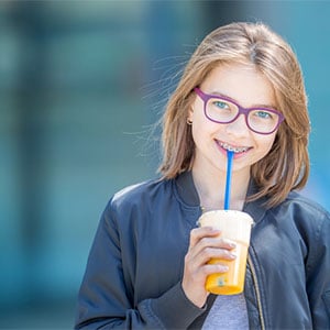preteen girl in braces smiling holding drink
