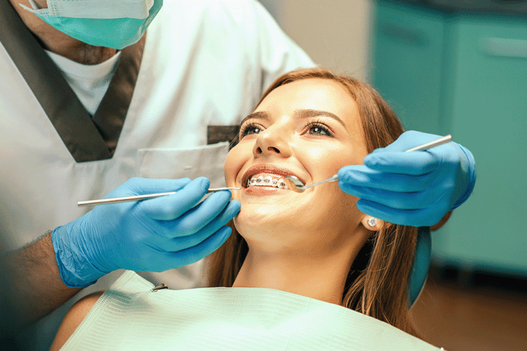 Orthodontist with a mask examining a teenage girl's braces.