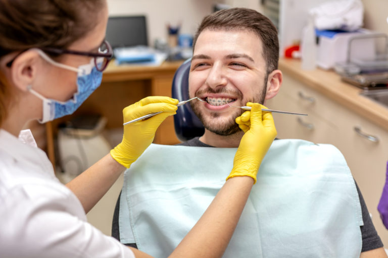 a man getting his braces inspected by a dental assistant
