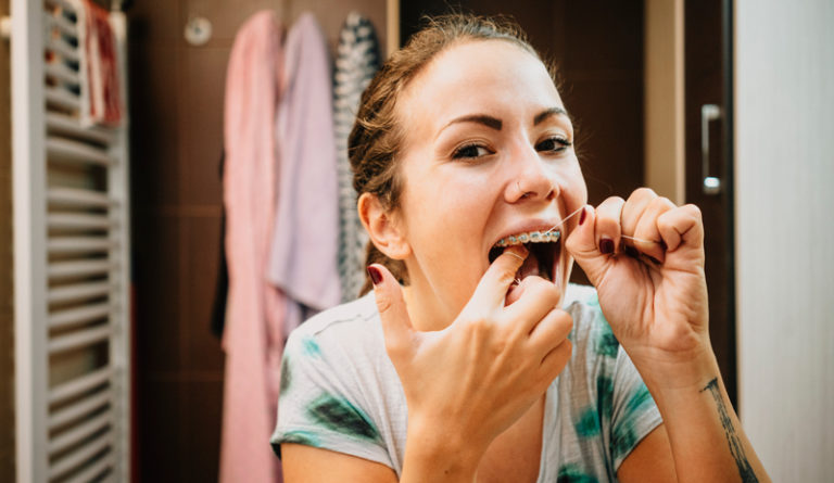 Woman flossing her teeth with dental floss