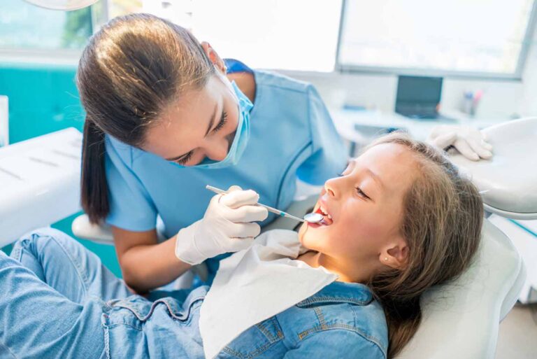 a dental assistant giving a little girl a dental exam