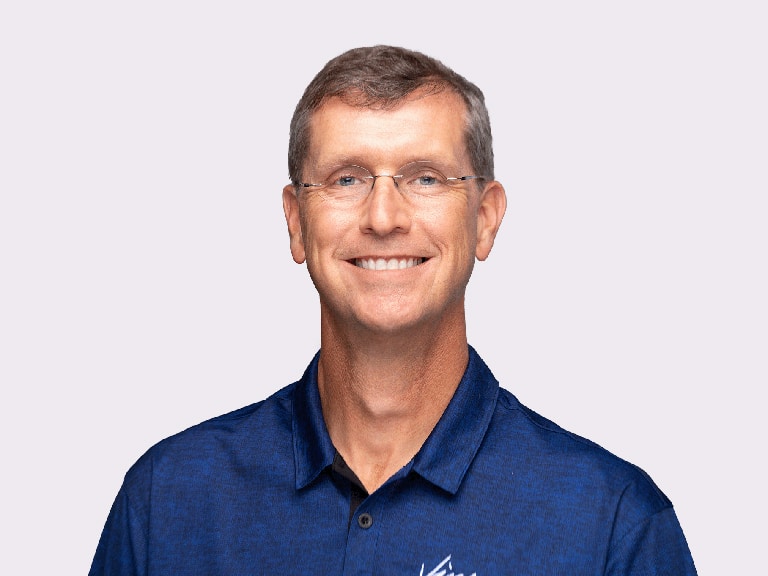 Dr. Vinson wearing a blue polo shirt, in front of a lavender background at the Wake Forest Office.
