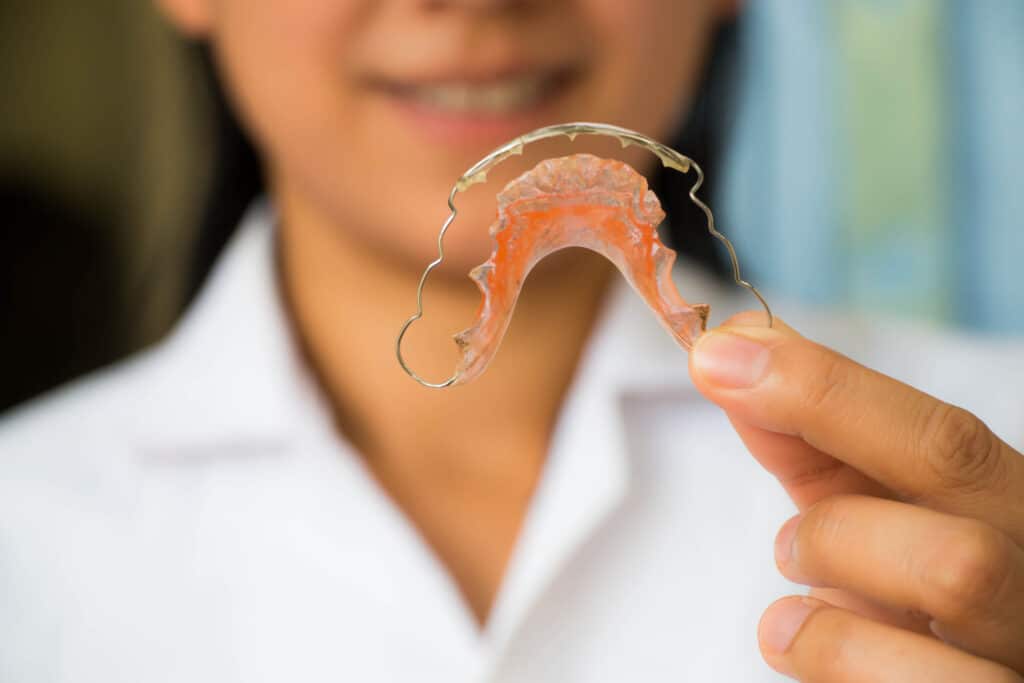 Orthodontic assistant displaying removable retainer to a patient