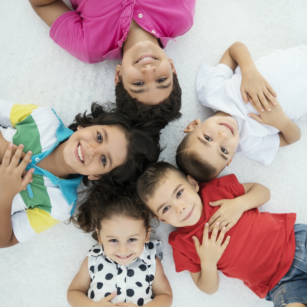 Group of children in bright, vibrant clothing laying together in a circle